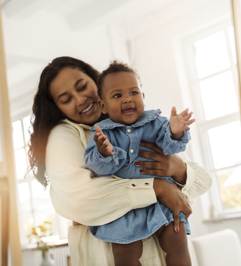 black-mother-taking-car-her-child (1) Young mother or babysitter with a little girl in her arms spin in the middle of the room.